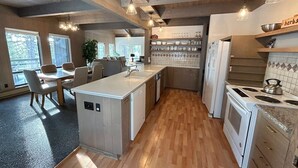 A modern kitchen with wooden beams, a central island, and a dining area with a view. - Tumbleweed Pines 3 Bedroom Home by RedAwning (Incline Village)