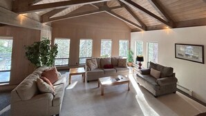 A spacious living room with high ceilings and large windows, furnished with sofas and a coffee table. - Tumbleweed Pines 3 Bedroom Home by RedAwning (Incline Village)