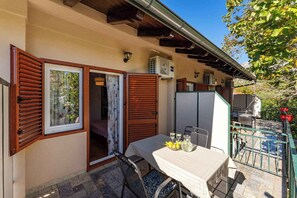 Eine Terrassenfläche mit einem Tisch für zwei Personen, einem Stuhl und einem kleinen Tisch mit einer Zitronenkörbchen und einer Flasche.