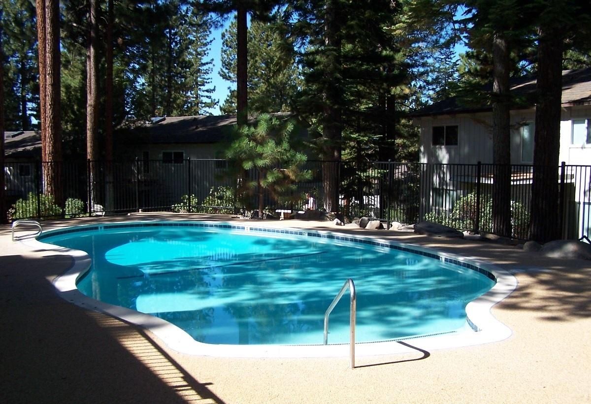 A community pool surrounded by trees and a fence.