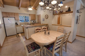 Una cocina compacta con armarios de madera, una isla central y una zona de comedor con mesa y sillas.