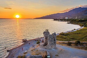 A coastal sunset view with ancient ruins and a clear sky.