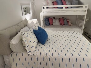 Une chambre avec un lit superposé, une table de chevet et un miroir.