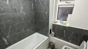 Ein Badezimmer mit Badewanne, Waschbecken und Fenster.