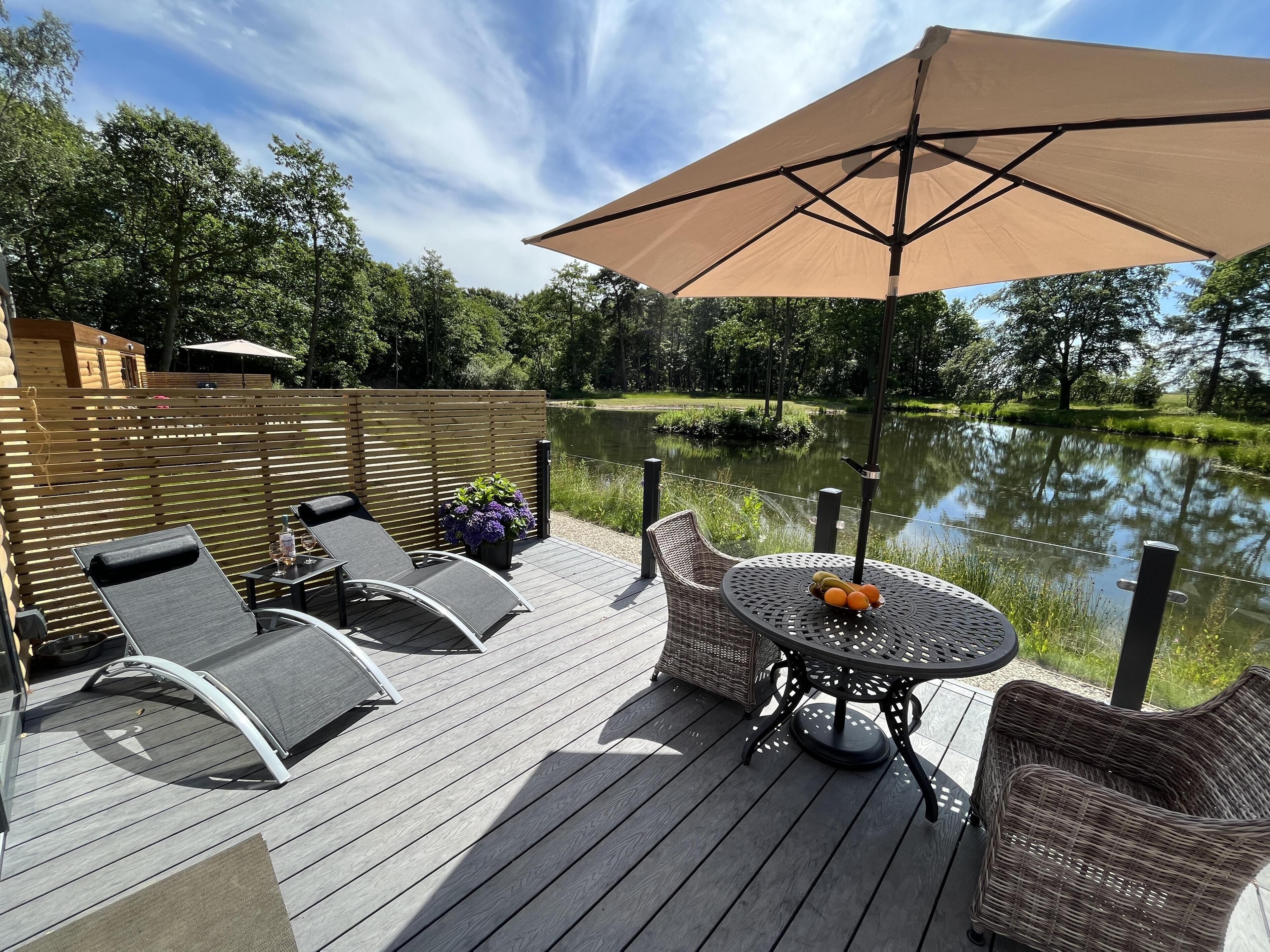 Une terrasse dotée de mobilier d’extérieur, une table garnie de fruits et une vue sur un lac.