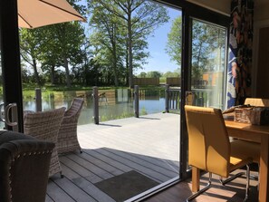 A deck with wicker chairs and a table, overlooking a lake and trees. - Pine Boutique Lodge With hot tub for Couples & dog (York)