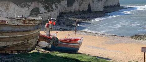 Deux bateaux sur une plage de sable, avec des falaises en arrière-plan.