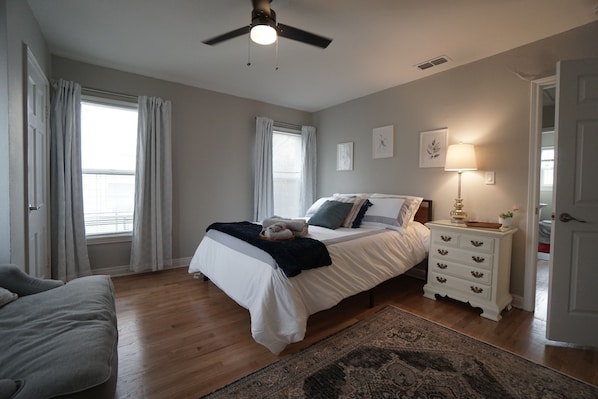 A bedroom with a bed, bedside table, lamp, and a ceiling fan.