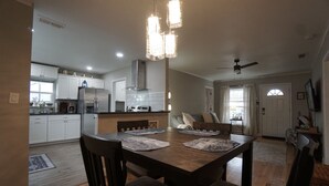 A spacious kitchen with white cabinets, a large island, and a dining area with a wooden table and chairs. - Cozy Cottage next to MSU Texas, centrally located!  (Wichita Falls)