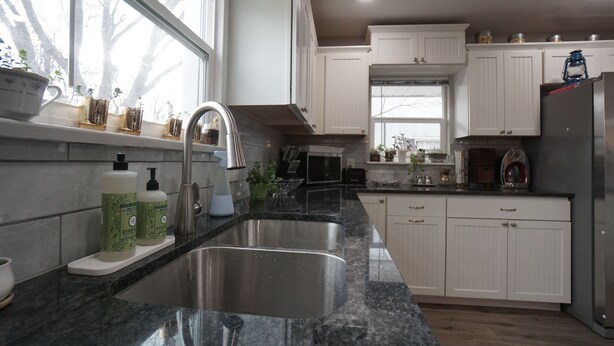 A modern kitchen with white cabinets, a granite countertop, stainless steel sink, and a window providing natural light. - Cozy Cottage next to MSU Texas, centrally located!  (Wichita Falls)