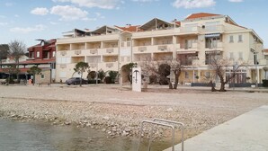 A multi-story hotel with balconies, a parking area, and a rocky riverbank. - Pet friendly apartment in Turanj with WiFi (Turanj)