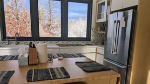 Eine moderne Küche mit großem Fenster, Holztisch und Edelstahlgeräten.