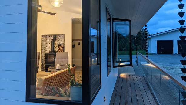 Ein modernes Haus mit Glastür, die zu einem Wohnbereich mit Kamin, einer Couch und einem Esstisch führt.