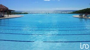 A large, clear blue pool with multiple lanes, surrounded by a deck area with lounge chairs.