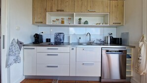 A modern kitchen with white cabinets, a stainless steel dishwasher, and a coffee maker on the countertop.