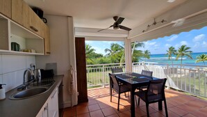 A kitchen with a view of the ocean, a dining area with chairs, and a ceiling fan.