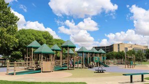 Ein Spielplatz mit Spielgeräten und begrünten Dachflächen, im Hintergrund ein Gebäude.