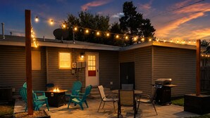 Ein Garten mit Sitzgelegenheiten, einem Grill und Lichterketten.