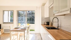 Een moderne keuken met een groot raam, een eethoek met een tafel en stoelen, en een spoelbak met kraan.