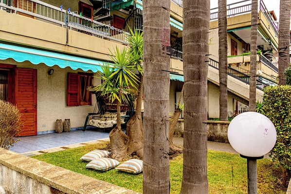 A courtyard with a palm tree, a bench, and a lamp post.