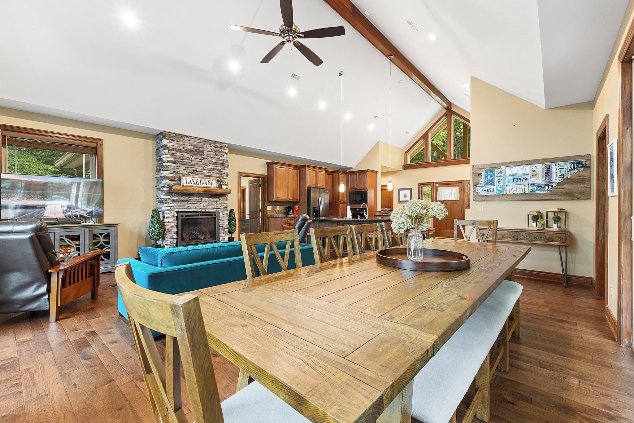 A spacious living area with a wooden dining table, blue sofa, and a stone fireplace.