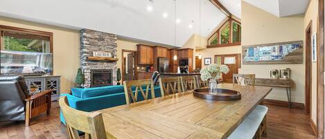 A spacious living area with a wooden dining table, blue sofa, and a stone fireplace.