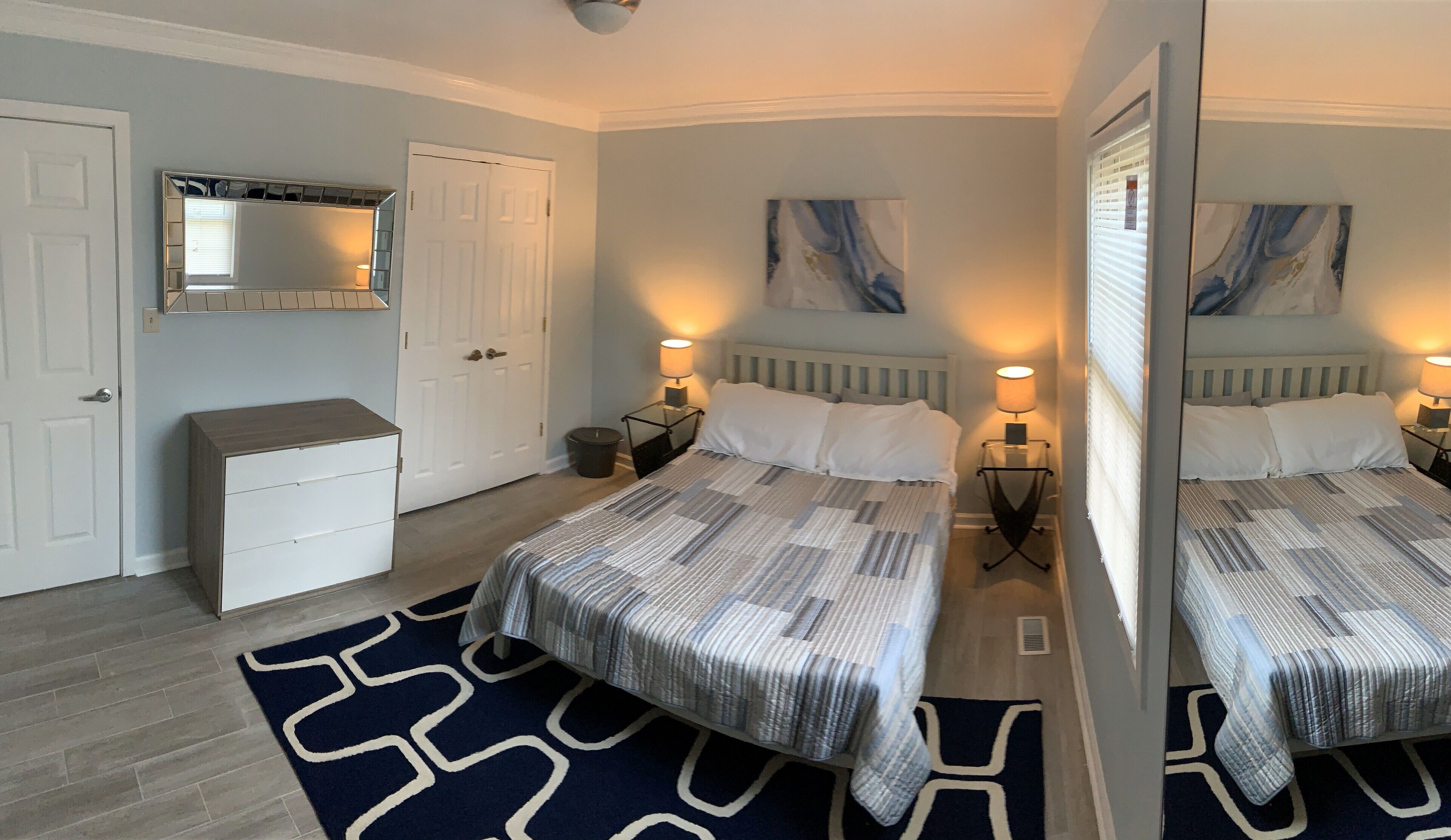 Une chambre avec deux lits, une commode, un miroir et des œuvres d’art accrochées aux murs.