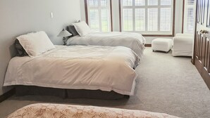 A bedroom with two beds, a small white chair, and large windows with blinds. - A poolside guest stay nested in a beautiful orchard along winery route (Niagara-on-the-Lake)