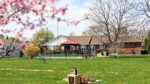 A residential area with a house, a fenced yard, and a picnic setup with wine bottles. - A poolside guest stay nested in a beautiful orchard along winery route (Niagara-on-the-Lake)