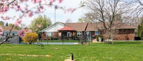 A residential area with a house, a fenced yard, and a picnic setup with wine bottles.