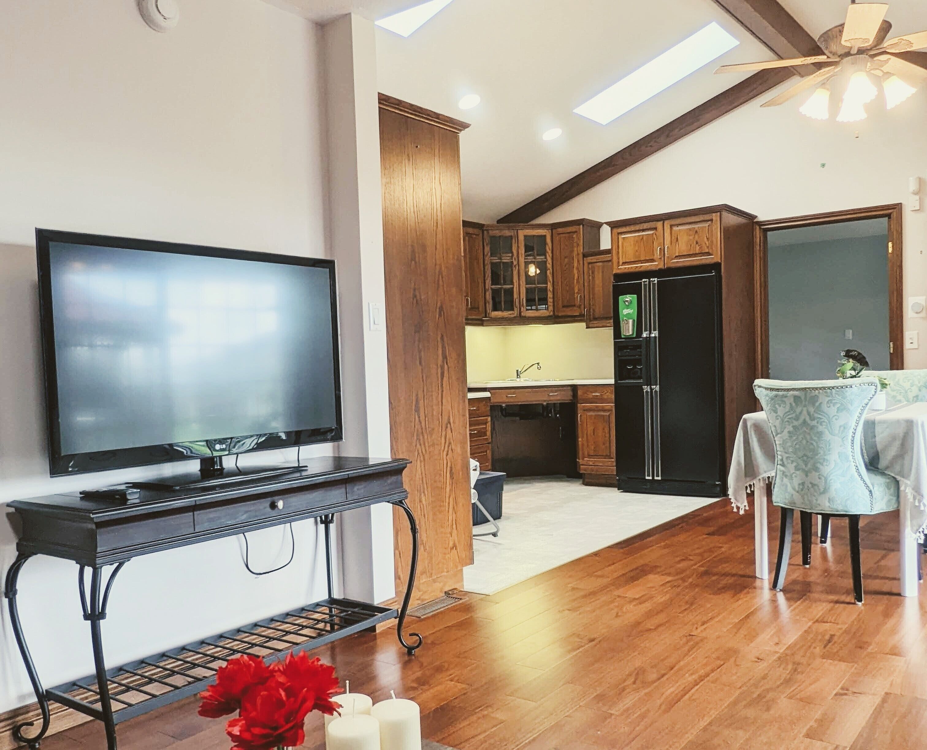 Una cucina moderna con mobili in legno, un frigorifero nero e un'area pranzo con tavolo e sedie.
