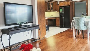 A modern kitchen with wooden cabinets, a black refrigerator, and a dining area with a table and chairs. - A poolside guest stay nested in a beautiful orchard along winery route (Niagara-on-the-Lake)