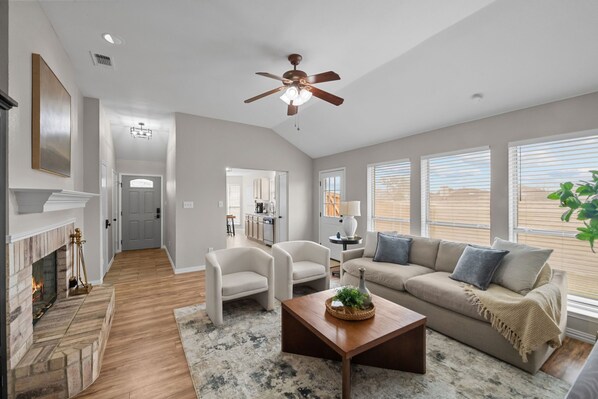A spacious living room with a fireplace, a ceiling fan, a sofa, and a coffee table.