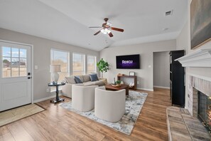 Un salon doté d’un ventilateur de plafond, d’un téléviseur à écran plat, d’une cheminée et d’un canapé.