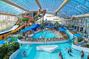 An indoor water park with multiple slides, a central pool, and seating areas.