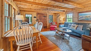 A wooden interior with a dining table, chairs, a sofa, and a coffee table. - Bayview Cottage Ephraim (Ephraim)