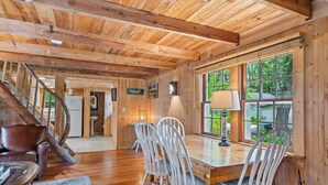 A wooden cabin interior with a dining area, a staircase, and a view of the outdoors. - Bayview Cottage Ephraim (Ephraim)