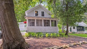 A white wooden house with a porch, surrounded by trees and a garden. - Bayview Cottage Ephraim (Ephraim)