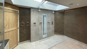 A modern bathroom with a skylight, a wooden door, and a shower with multiple heads. - Gorgeous home in Hellendoorn with sauna (Hellendoorn)
