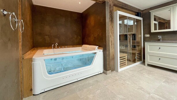 A modern bathroom with a large bathtub, a glass shower enclosure, and a vanity with a mirror. - Gorgeous home in Hellendoorn with sauna (Hellendoorn)