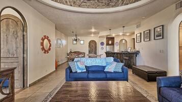 A spacious living room with a blue sofa, a wooden coffee table, and a stone ceiling.
