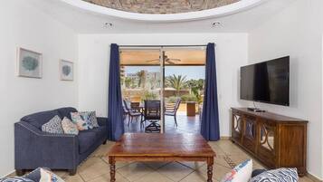 A living room with a sofa, a coffee table, a TV, and a view of the outdoors through a glass door.