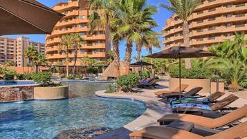 A resort pool area with lounge chairs and palm trees.