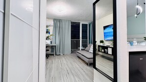 Uma sala de estar moderna com um espelho grande, um sofá e uma televisão.