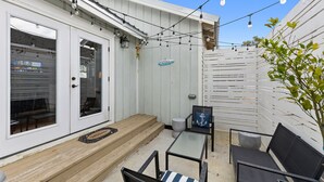 A patio with outdoor furniture, a wooden deck, and string lights. - Main Street Pool and Hot Tub Oasis BSL 039 (Bay St. Louis)