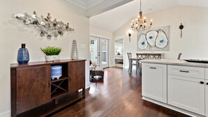 A spacious kitchen with white cabinets, a wooden dining table, and a chandelier. - Main Street Pool and Hot Tub Oasis BSL 039 (Bay St. Louis)