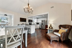 A spacious kitchen with modern appliances, a dining area with white furniture, and a cozy seating area with patterned upholstery.