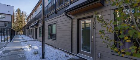 A row of townhouses with a covered walkway, large windows, and a balcony on the upper floor.