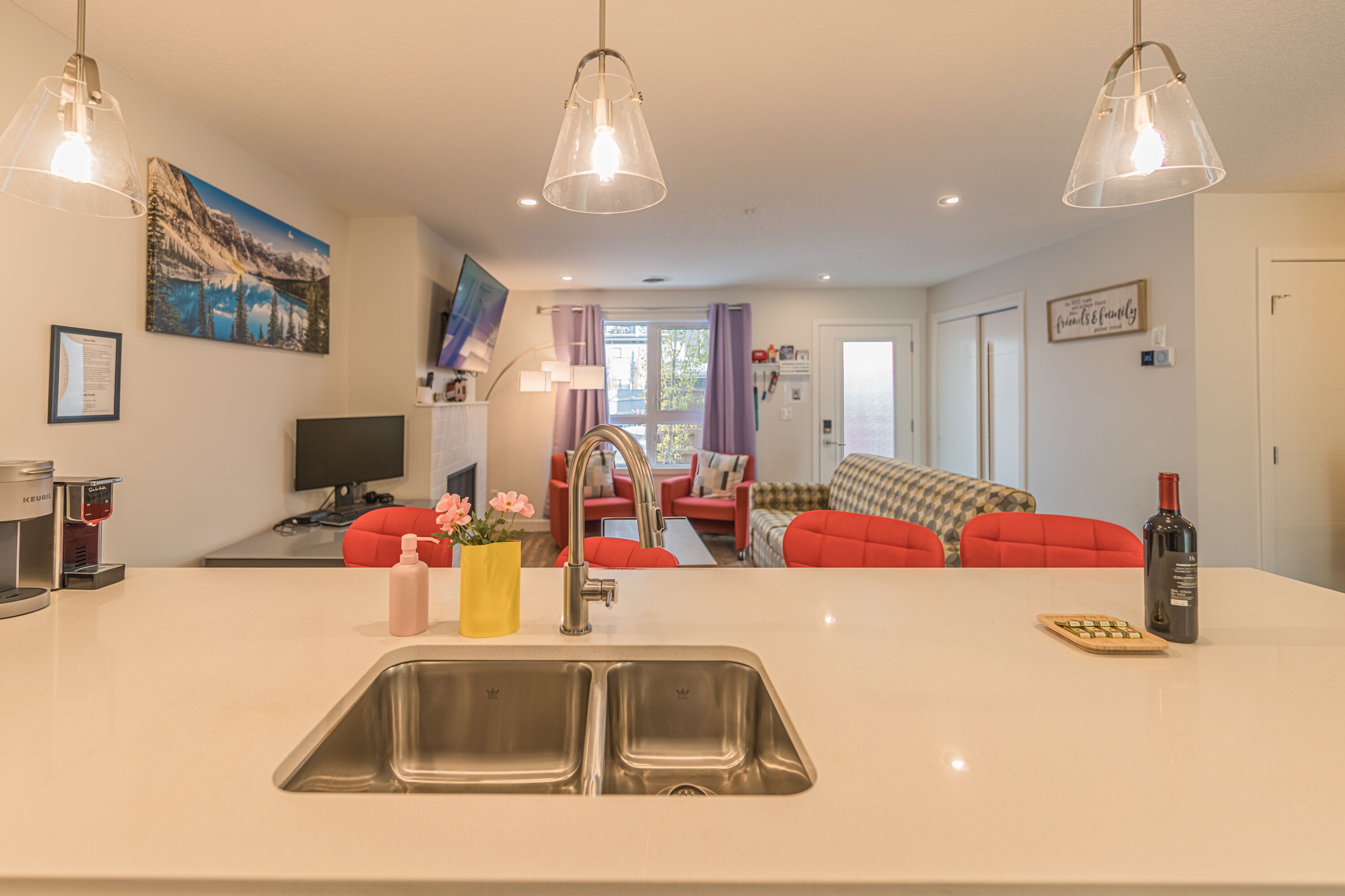 A modern kitchen with a central island, stainless steel sink, and pendant lighting.