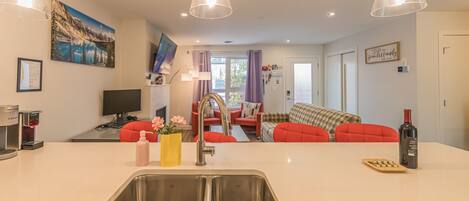 A modern kitchen with a central island, stainless steel sink, and pendant lighting.